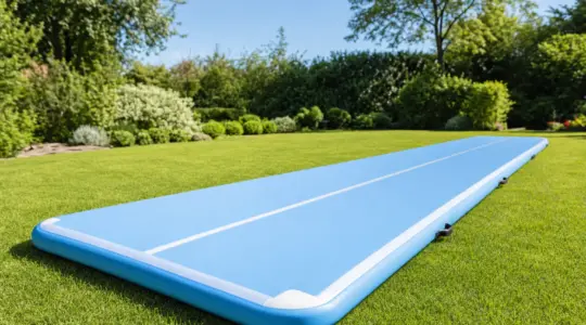 Eine lange, aufblasbare Airtrack-Turnmatte in frischer Farbe liegt einladend auf einer grünen Rasenfläche im Garten