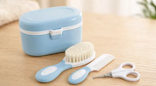Ein Baby-Pflegeset mit weicher Babybürste, Kamm, abgerundeter Nagelschere und kleiner Pflegebox in zarten Farben ordentlich angeordnet auf einem hellen Holztisch