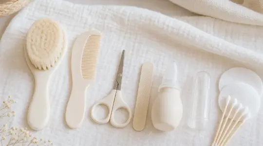 Ein Babypflege-Set mit weicher Bürste, Kamm, Nagelschere und weiteren Pflegehelfern liegt ordentlich nebeneinander