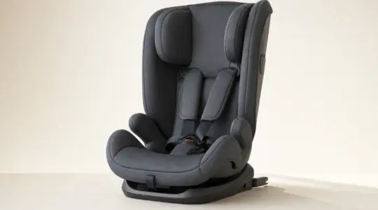 Ein moderner Kindersitz für das Auto mit hoher Rückenlehne und Seitenaufprallschutz steht auf einer hellen Fläche