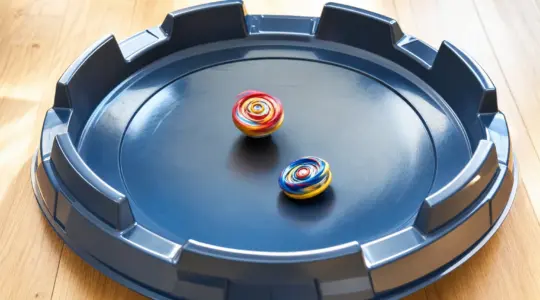 Eine runde schalenförmige Spielzeug-Arena aus Kunststoff mit zwei Kreiseln auf einem Holzboden