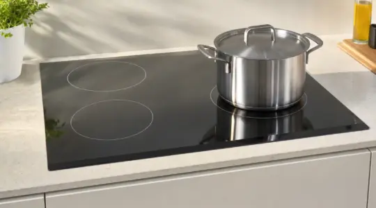 Ein modernes Ceranfeld ist in eine helle Küchenarbeitsplatte eingebaut, darauf steht ein Topf