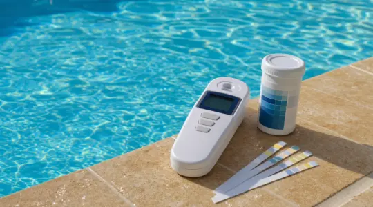 Ein digitales Pool-Wassertestgerät am Rand eines Swimmingpools