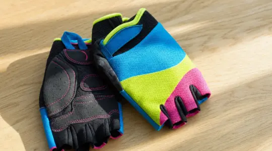 Ein Paar bunte Kinder-Fahrradhandschuhe mit kurzen Fingern auf einer Holzfläche
