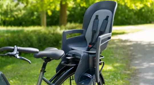 Ein sicherer Kinderfahrradsitz mit hoher Rückenlehne und gepolstertem Gurt ist am Gepäckträger eines Fahrrads montiert