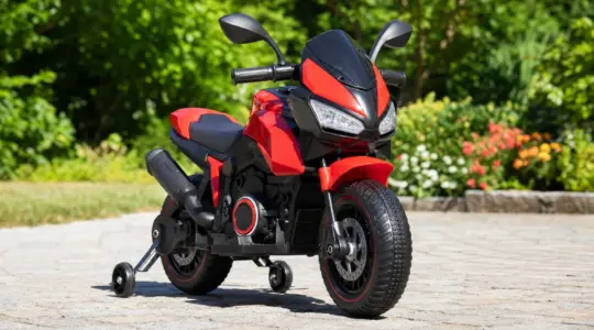 Ein farbenfrohes Kindermotorrad steht einsatzbereit auf einem sonnigen gepflasterten Hof vor grünem Hintergrund