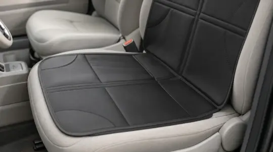 Eine schwarze Schutzunterlage aus Kunststoff ausgebreitet auf einem hellen Autositz in neutralem Grau, schützt den Sitz vor Abdrücken