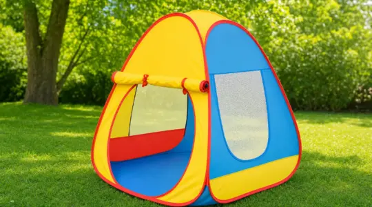 Ein farbenfrohes Pop-up-Kinderzelt steht aufgebaut auf einer sonnigen Wiese im Garten und lädt zum Spielen ein