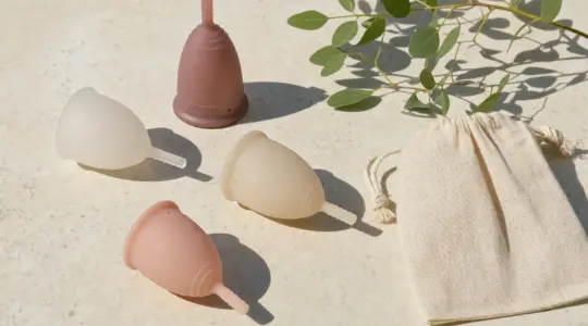 Mehrere Menstruationstassen aus Silikon in verschiedenen Farben liegen auf einem Tisch