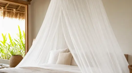 Ein weißes Moskitonetz hängt über einem Bett in einem hellen Schlafzimmer