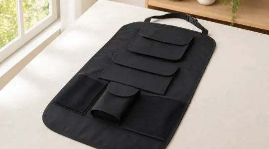 Ein Rückenlehnenschutz für den Autositz mit Taschen liegt ausgebreitet auf einer hellen Fläche