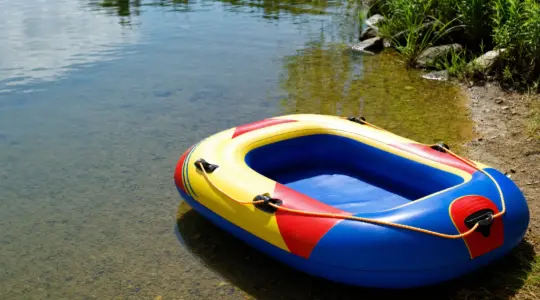 Ein aufblasbares Schlauchboot für Kinder liegt an einem ruhigen Ufer bereit