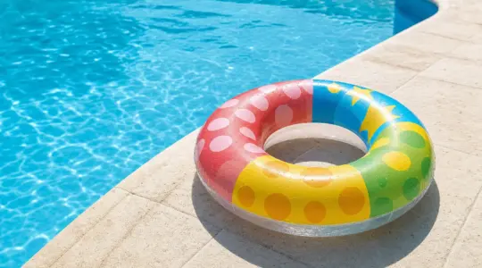 Ein bunter aufblasbarer Schwimmring für Kinder am Rand eines Swimmingpools