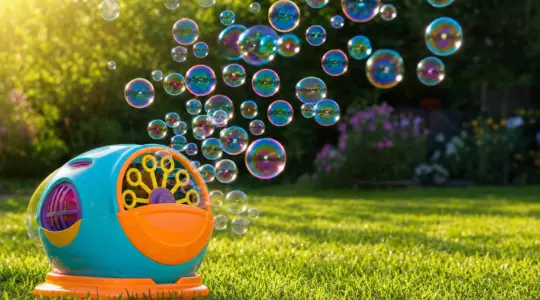 Eine bunte Seifenblasenmaschine produziert viele schwebende Seifenblasen im Garten