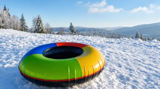 Ein bunter aufblasbarer Snowtube-Rodelreifen auf einer verschneiten Wiese