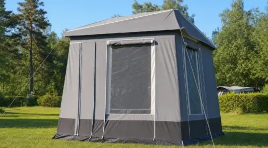 Ein großes graues Steilwandzelt steht auf einer Wiese auf einem Campingplatz