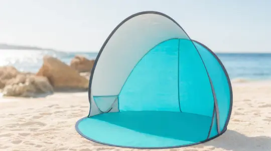 Aufgestellte Strandmuschel als Pop-up-Strandzelt mit UV-Schutz in freundlicher Farbe auf hellem Sand am Strand