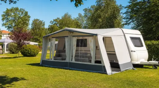 Ein aufgebautes Vorzelt an einem Wohnwagen auf einem sonnigen Campingplatz